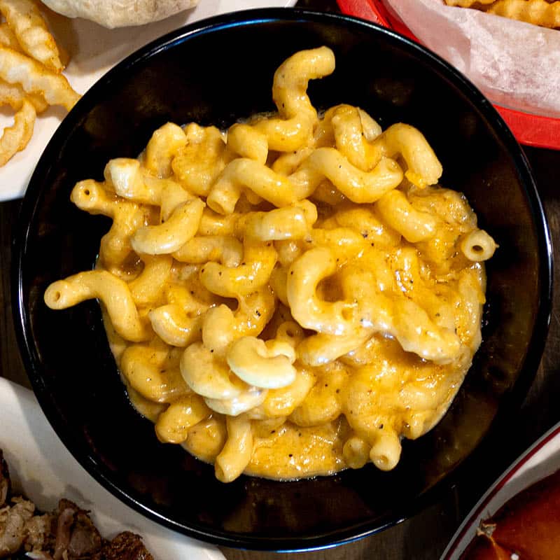 A close-up overhead shot of a black bowl filled with creamy cavatappi mac and cheese from Brewski's Sports Club & BBQ.
